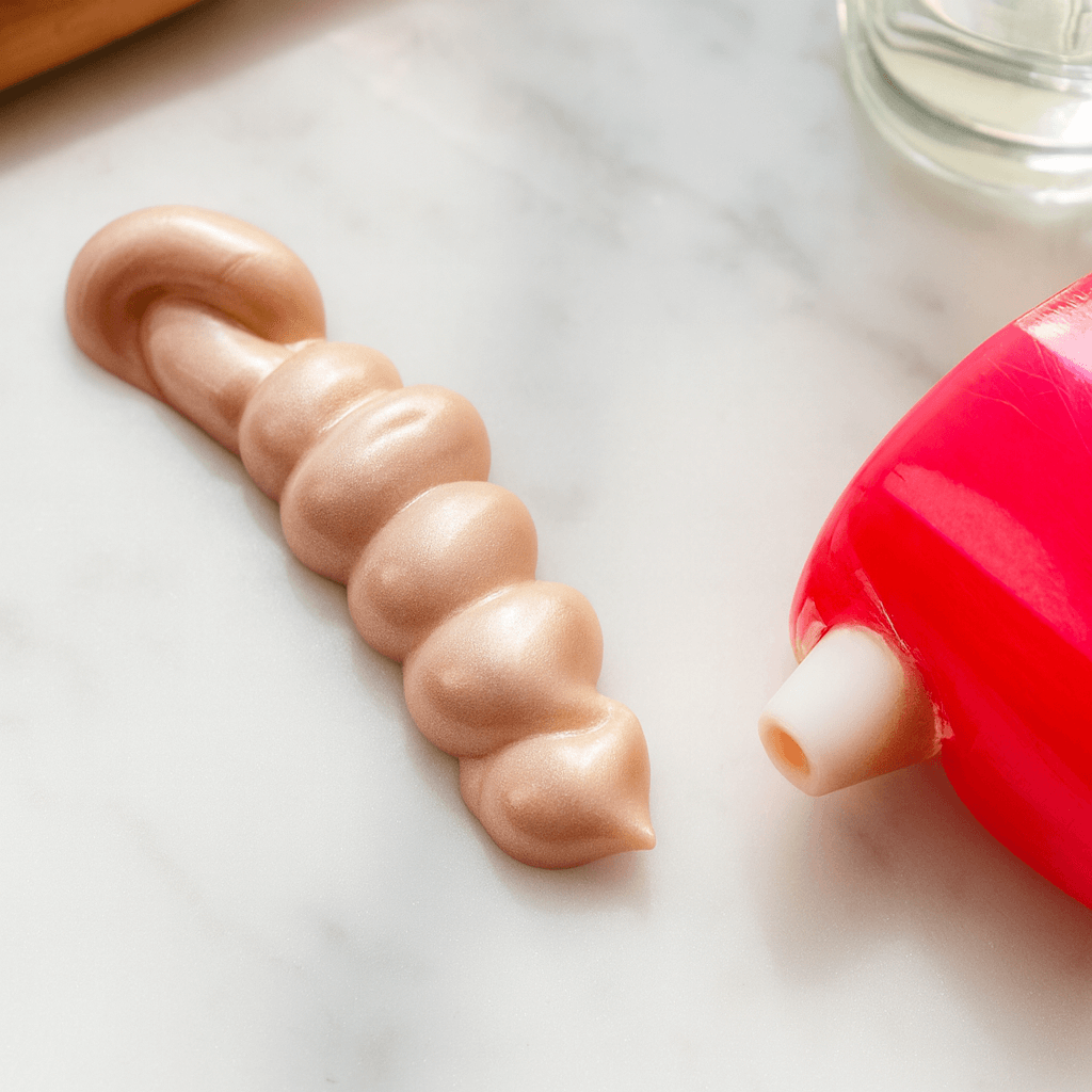 Lucky Chick Dawn Glow Fruit-Infused Illuminizer pumped from tube onto marble surface, showing creamy champagne shimmer texture.