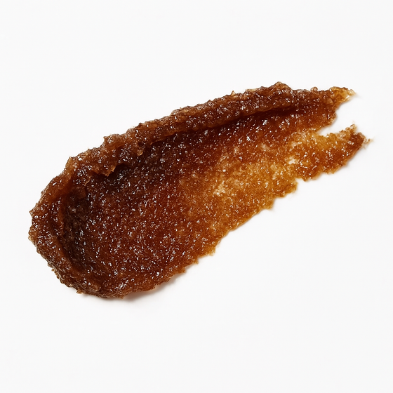 A close-up of Lucky Chick’s Sweet Vanilla Sugar Lip Scrub swatched on a white background, showing its rich brown sugar texture and glossy exfoliating formula.